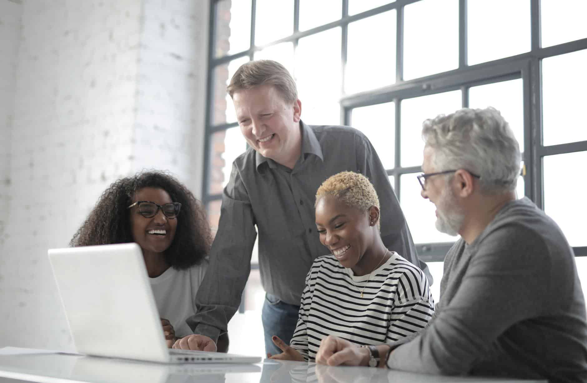 smiling multiracial colleagues surfing laptop in creative office
